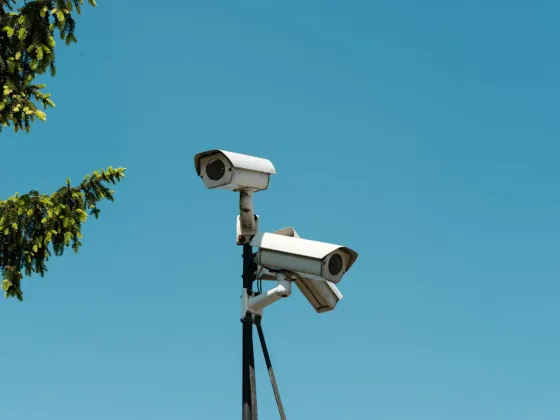 Two CCTV cameras mounted on a pole against a blue sky