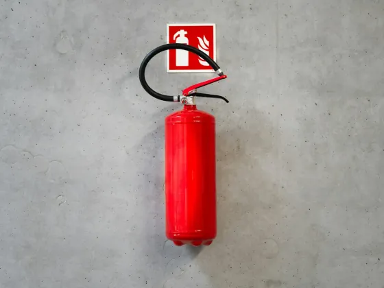Fire extinguisher mounted on a concrete wall with its safety sign