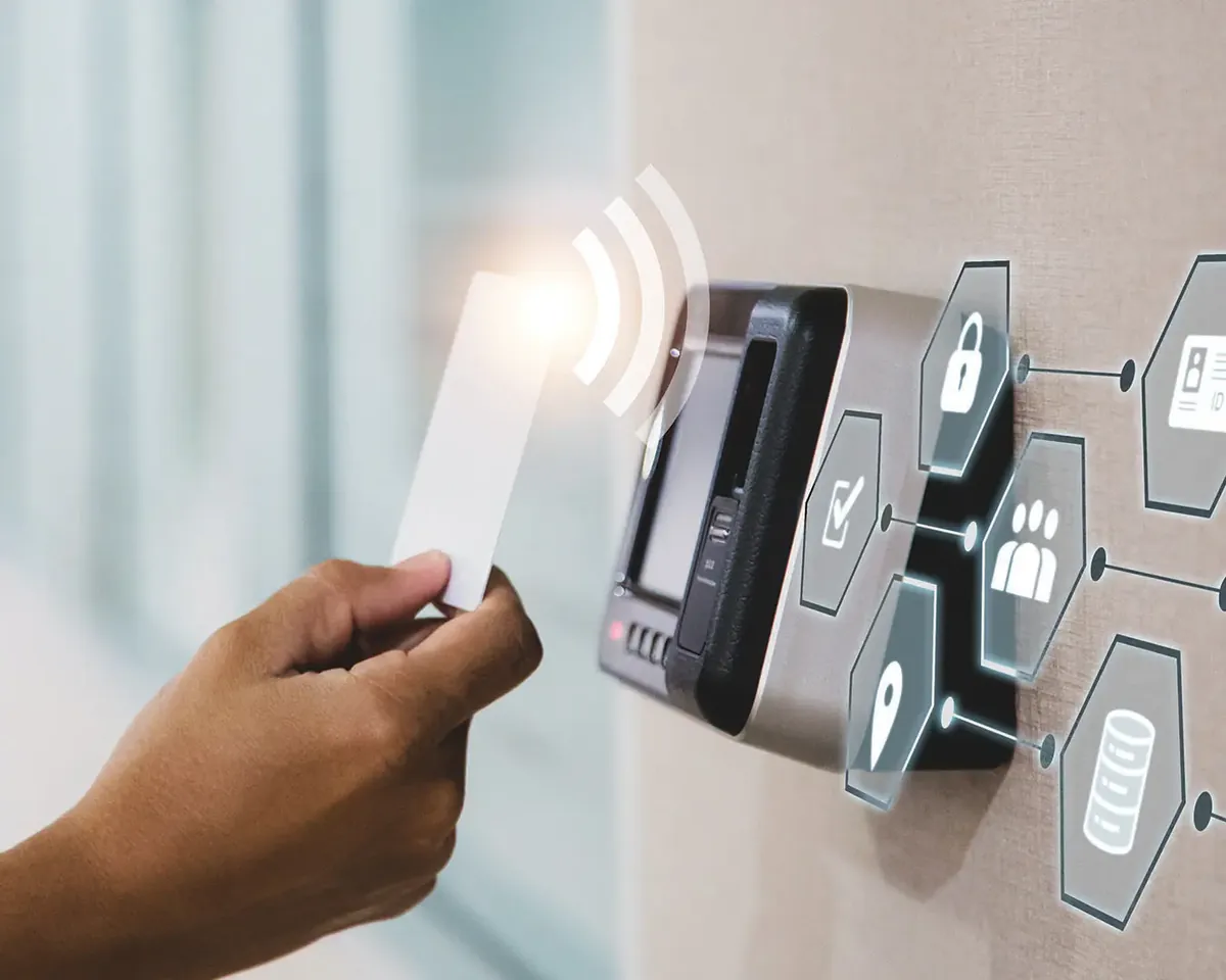 Hand presenting an access card to a wall-mounted reader